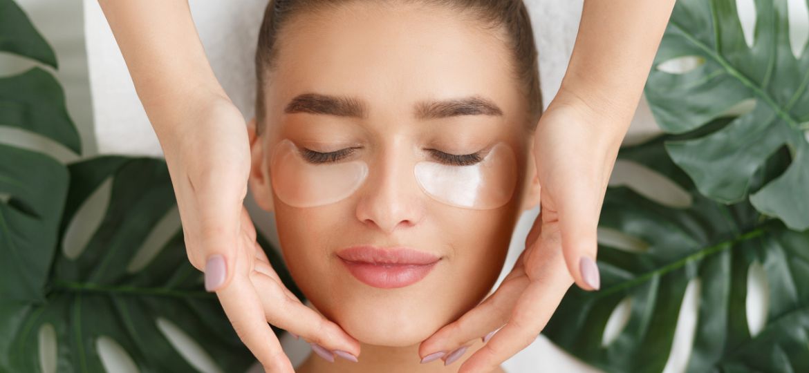 Woman with eye patches having face massage
